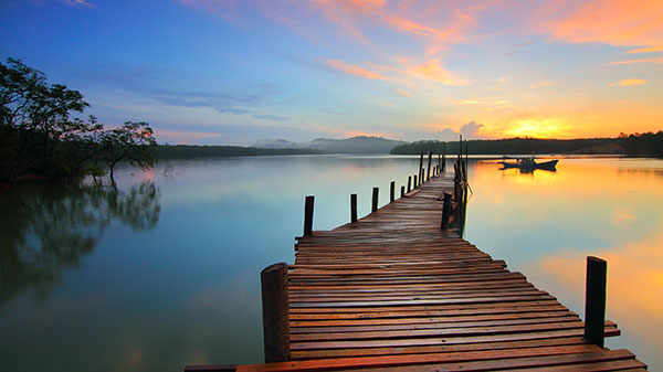 Photo of sun rising over lake with dock in foreground