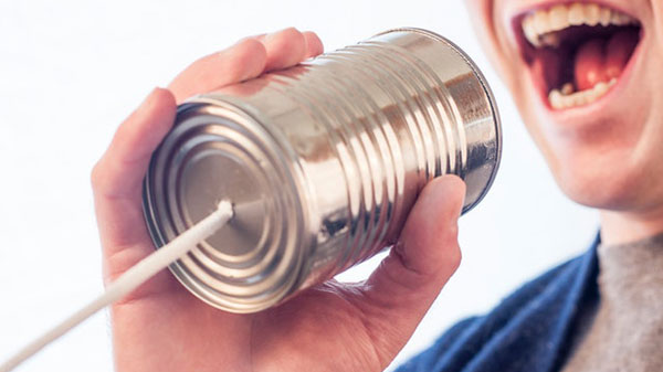 Photo of a man talking into a "can telephone"