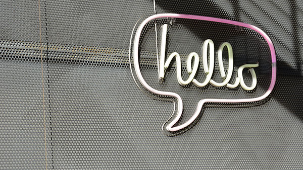 Photo of a neon sign on a wall that spells "hello" in a word balloon.