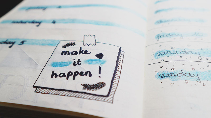 Photo of a day planner with a note, "Make it happen!"